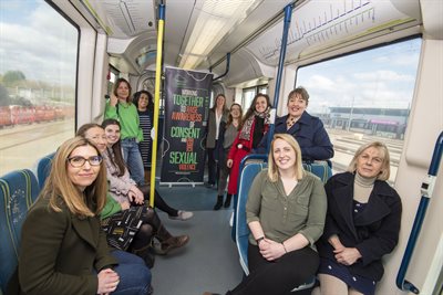 A group of females on a tram with the consent coalition banner in the background