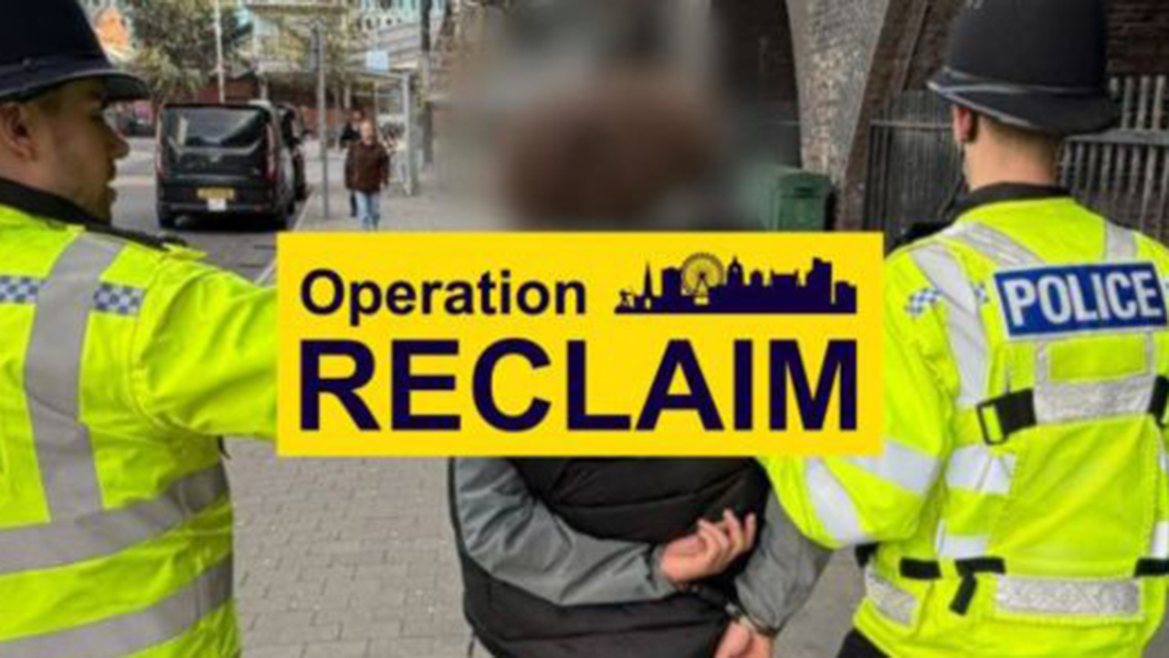 Two officers making an arrest with an Operation Reclaim banner