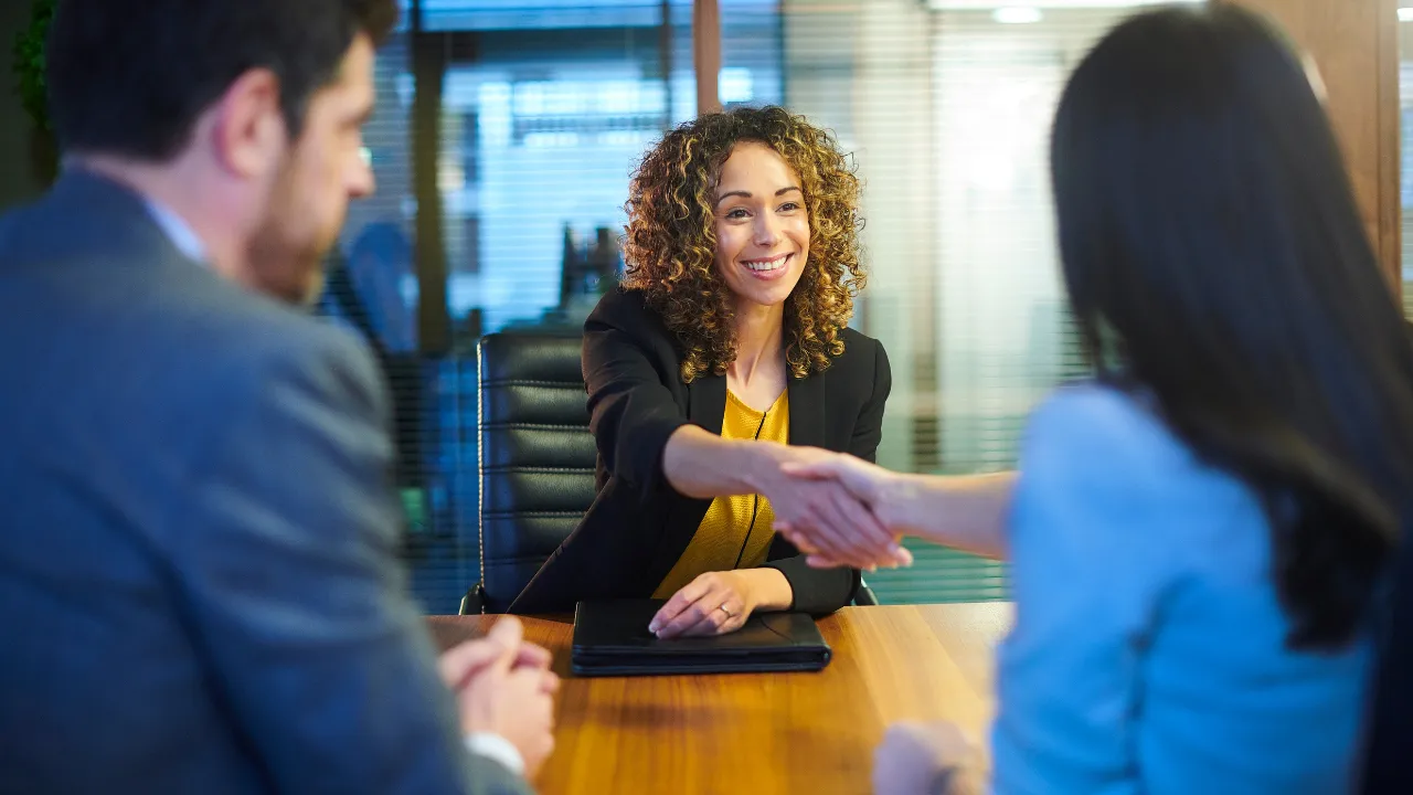 Smiling woman shaking hands at a job interview.
