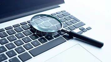 image of a magnifying glass on a laptop to signify scrutiny of data